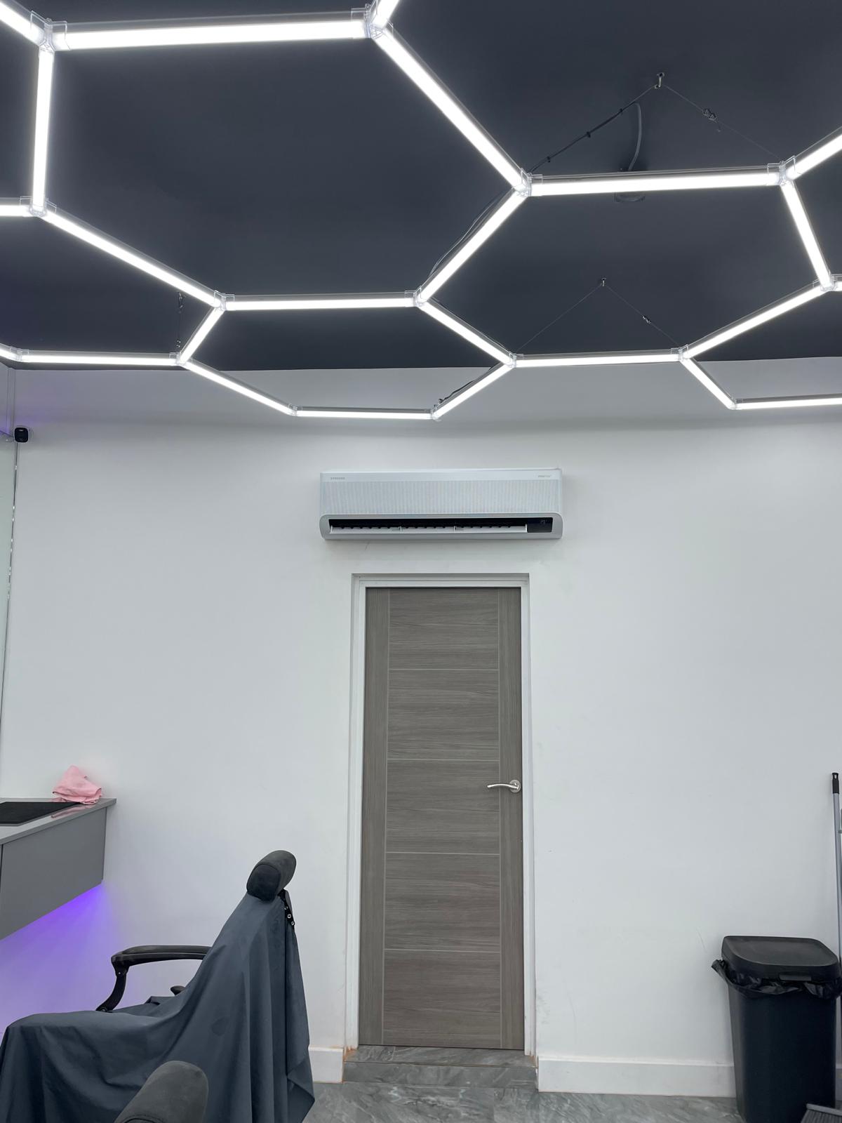Wall-mounted air conditioning unit installed above a doorway in a barbershop